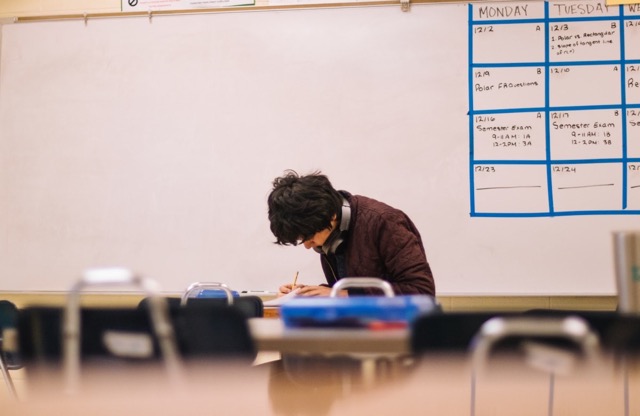 a student alone in a classroom doing work.